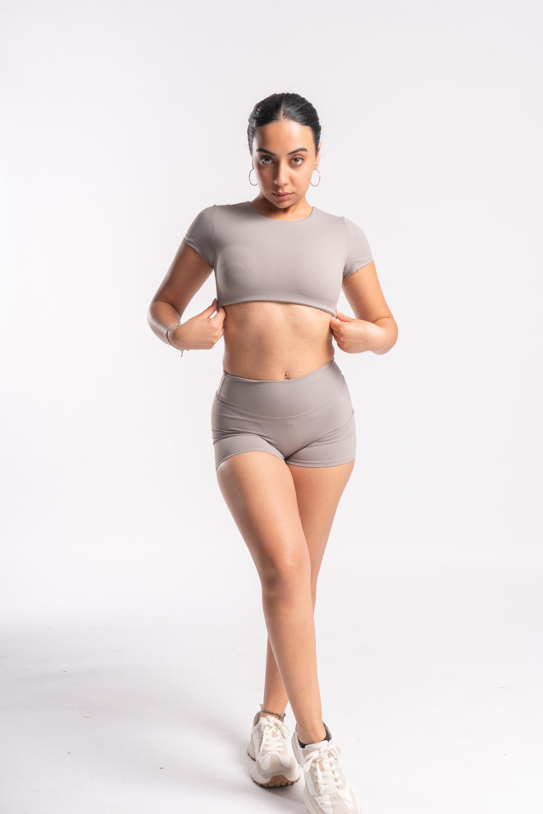 Athletic woman in beige two-piece workout set of shorts and crop top