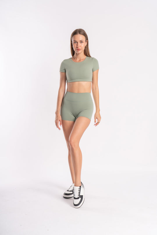 Model wearing green fitness set - crop top and shorts